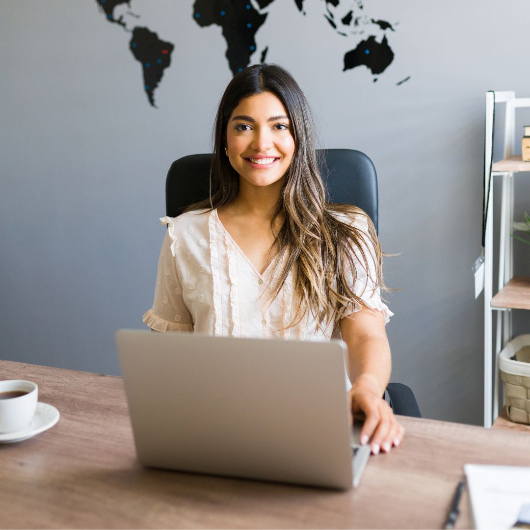 Luxury travel consultant working at her desk in front of a world map, planning bespoke itineraries for agency clients.